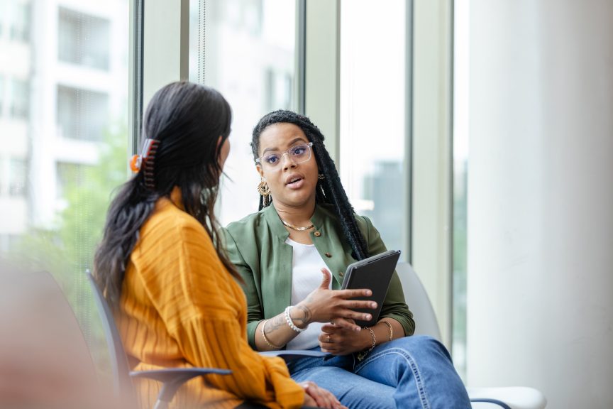 An attentive young woman listens to a caring female counselor's advice.